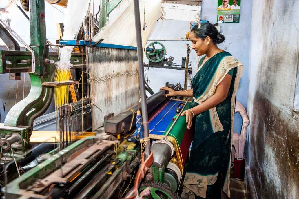 One of the women working on Mottusami’s team, changes the threads and checks the accuracy of the loom.